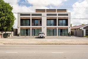 A modern multi-story building with a parking lot in front.