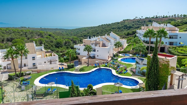 A resort with multiple swimming pools, lush greenery, and a view of the sea. - Terrazas de Alcaidesa 2437 Penthouse (San Roque)