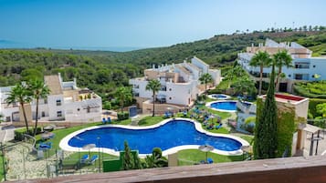 Un resort con varias piscinas, exuberante vegetación y vista al mar.