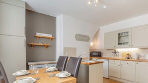 A modern kitchen with a dining area, wooden cabinets, a microwave, and a sink. - 2 bedroom accommodation in Colwyn Bay (Colwyn Bay)