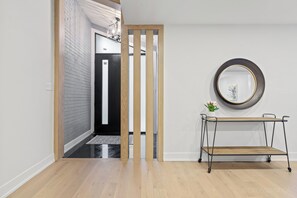 Contemporary hallway with a sliding door, mirror, and console table, offering a simple and functional space.