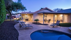 Um quintal residencial com piscina, móveis de pátio e área de estar coberta ao ar livre.