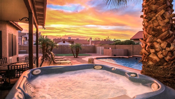 Un bain à remous avec piscine, des palmiers et une vue sur le coucher de soleil.