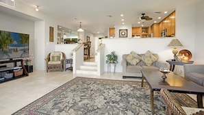 A spacious living area with a flat-screen TV, a sofa, a coffee table, and a dining area with chairs.