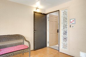 Ein Zimmer mit einer Korbsitzbank, einer Tür mit einem Schutzgitter und einer Wandplatte.