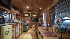 A cozy interior with wooden paneling, a kitchen area with modern appliances, and a dining space with a table and chairs.