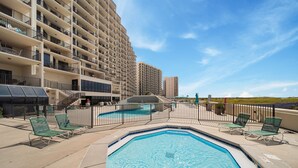 A swimming pool with lounge chairs and a fenced area, surrounded by high-rise buildings.