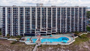 A high-rise hotel with multiple balconies, a swimming pool, and a landscaped area.