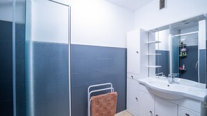 Une salle de bain moderne avec une douche à parois de verre, un lavabo blanc avec un miroir et un porte-serviettes.