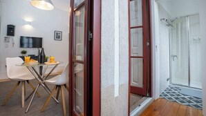 Een moderne woonkamer met een eethoek, een televisie en een douchecabine van glas.