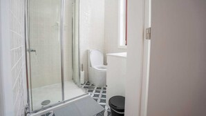 Een badkamer met een douchecabine van glas, een toilet en een wastafel.