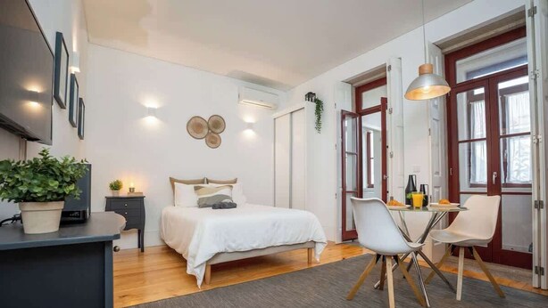 Een moderne slaapkamer met een bed, nachtkastje en een bureau met stoelen.
