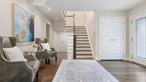 Un vaste espace de vie agrémenté d’un escalier moderne, d’un grand tableau abstrait et d’un tapis à motifs.