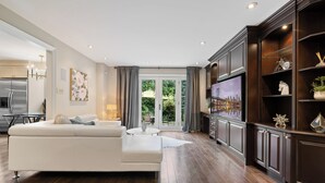 Un salon moderne avec un canapé blanc, un téléviseur et un meuble en bois.