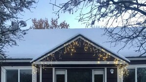 Une maison à l’extérieur sombre, avec des boiseries blanches et une porte noire. Elle comporte trois fenêtres à l’avant, et le numéro 316 est visible sur le mur.