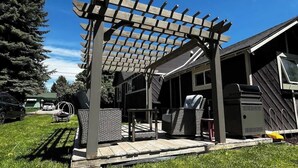 Un patio couvert agrémenté d’une pergola, de mobilier d’extérieur et d’un barbecue.