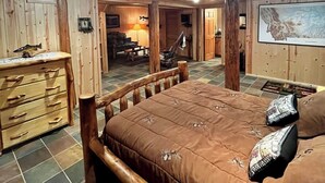 A wooden cabin interior with a large bed, wooden dresser, and a dining area. - Timberline Cabin Near Bozeman! (Bozeman)