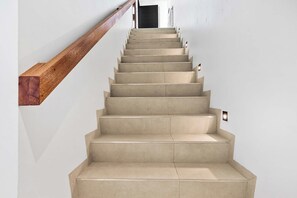 Eine Treppe mit einem hölzernen Geländer und Leuchten auf jedem Stufenabsatz.
