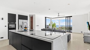 Eine moderne Küche mit einer großen Kochinsel, eingebauten Geräten und Blick ins Freie.