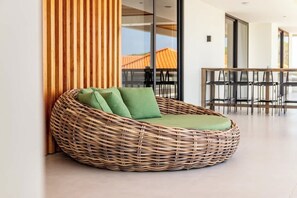 Ein rattengewebtes Sofa mit grünen Kissen in einem modernen Innenraum.
