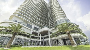A modern high-rise hotel with a curved facade, multiple balconies, and palm trees in the foreground. - Sandy Homestay Citadines Marina Ha Long is a great choice for accommodation (Ha Long)