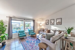 Relax in this stylish living room with a sofa set, coffee table, and side table, offering a view of the balcony.