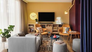 Una sala de estar moderna con un sofá, dos sillones, una mesita de centro, un televisor y un letrero de neón.