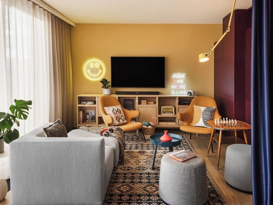 Una sala de estar moderna con un sofá, dos sillones, una mesita de centro, un televisor y un letrero de neón.