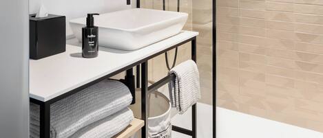 A modern bathroom with a glass-enclosed shower, a white sink, and a towel rack.