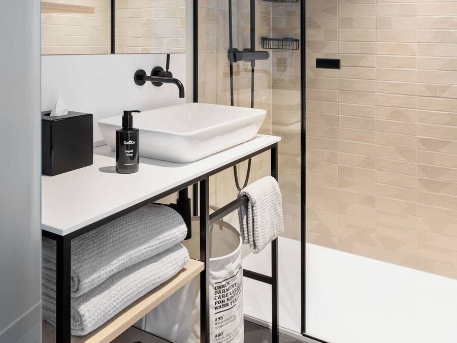 A modern bathroom with a glass-enclosed shower, a white sink, and a towel rack.
