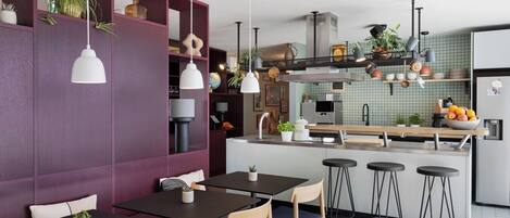A modern kitchen with a central island, bar stools, and pendant lighting.