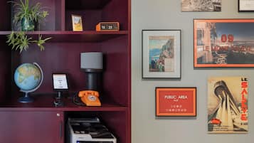 Una pared con cuadros enmarcados, un reloj, un globo terráqueo, un teléfono y una impresora.