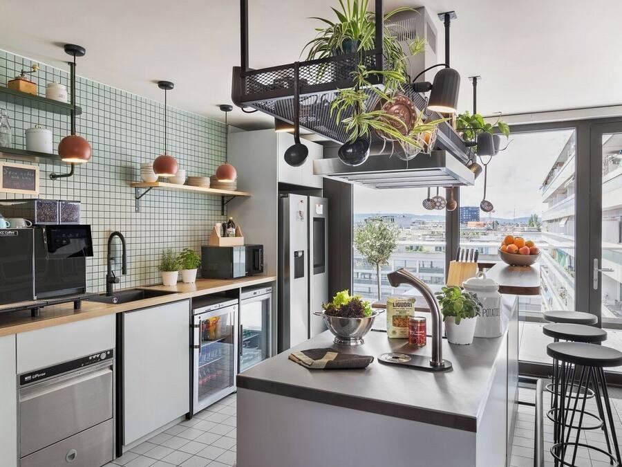 A modern kitchen with a coffee machine, a sink, and a window overlooking a cityscape.