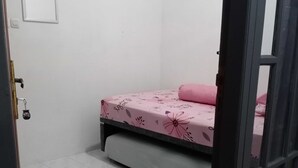Een kleine, schone kamer met een bed, een deur en een betegelde vloer.