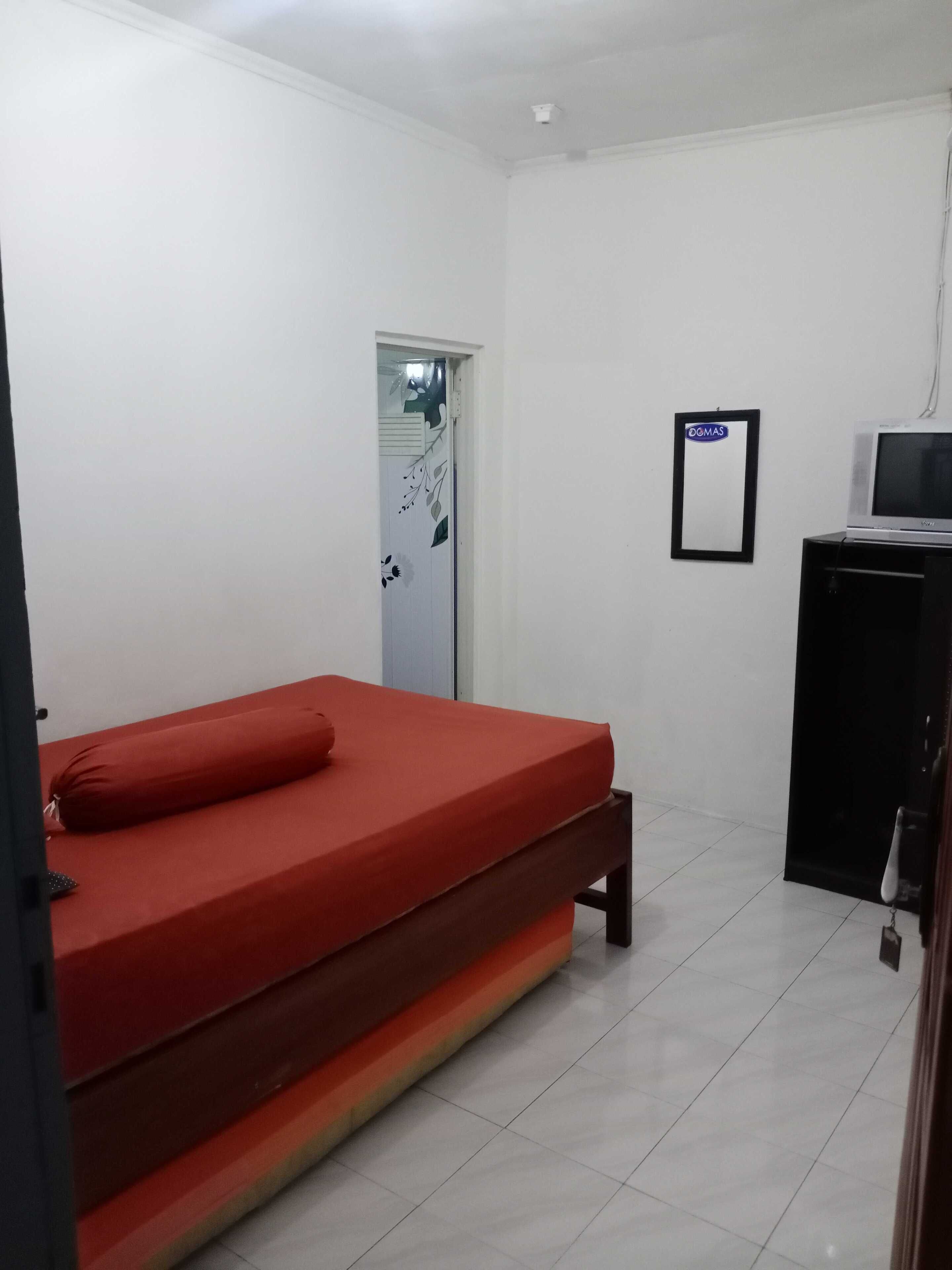 Una habitación con una cama individual, un escritorio pequeño con televisor y una puerta con un letrero.