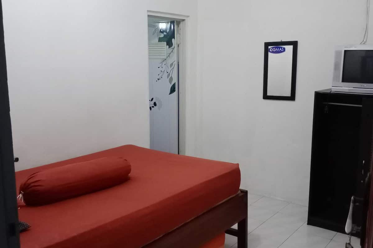Une chambre avec un lit simple, un petit bureau avec une télévision et une porte sur laquelle est apposée une pancarte.