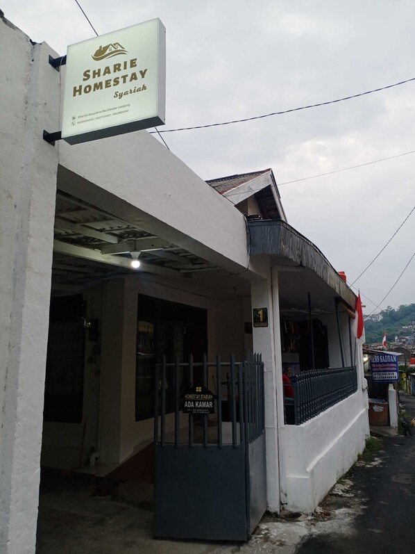A two-story building with a sign for 'SHARIE HOMESTAY Syariah' at the top.