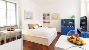 Un dormitorio moderno con cama, escritorio, televisor y estantería.