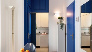 Una cocina moderna con armarios azules, un lavavajillas y un comedor con una mesa y un cuenco de fruta.