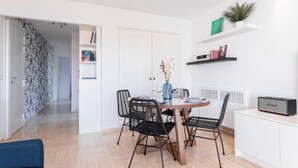 A modern kitchen with a dining table, chairs, and a radio. There are shelves with books and a plant. - Cocoon with garden near the sea (Cannes)