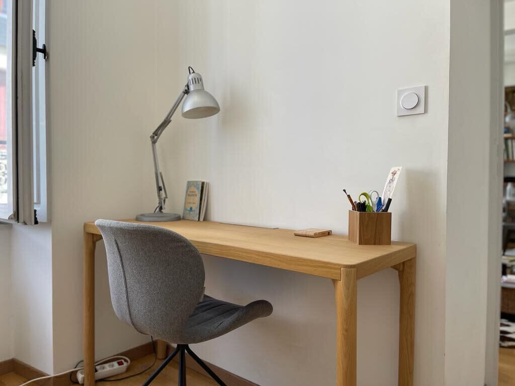 A workspace with a desk, chair, lamp, and a wall-mounted light switch.