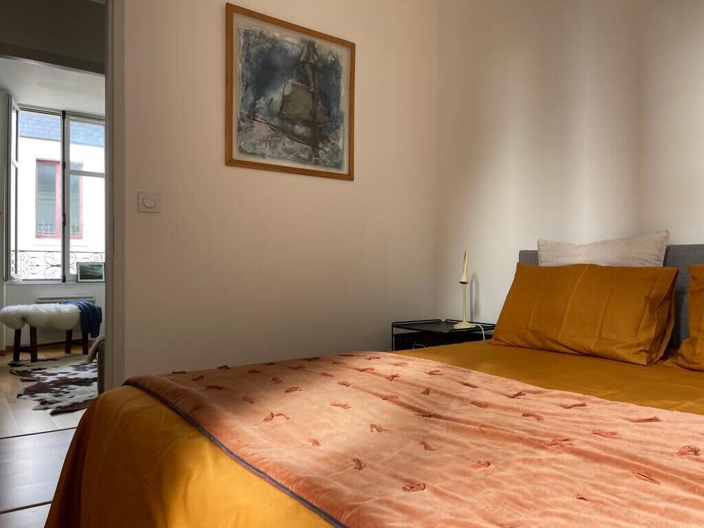 Ett sovrum med en säng, ett nattduksbord, en lampa och en tavla på väggen.