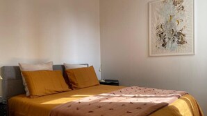 Ein Schlafzimmer mit einem Bett, zwei Kissen, einem Nachttisch und einem Wandbild.