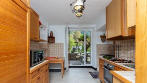 A kitchen with wooden cabinets, a microwave, a stove, and a sink. - La rivière de St Meme (Saint-Pierre-d'Entremont)