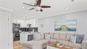 Un salon moderne avec un canapé d’angle, une table basse et un ventilateur de plafond.