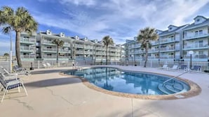 Un hôtel doté d’une piscine, de palmiers et de nombreux balcons.