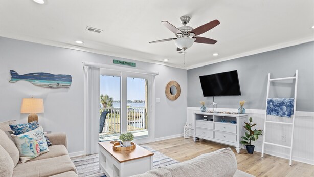 Un salon moderne doté d’un ventilateur de plafond, d’un téléviseur et d’un balcon avec vue.
