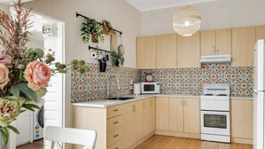 Une cuisine avec des meubles en bois, un four blanc, un four à micro-ondes et une plante suspendue.