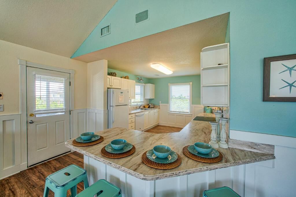 A kitchen with a central island, white cabinets, and a teal wall.