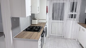 Una cocina moderna con encimera de madera, estufa a gas y armarios blancos.